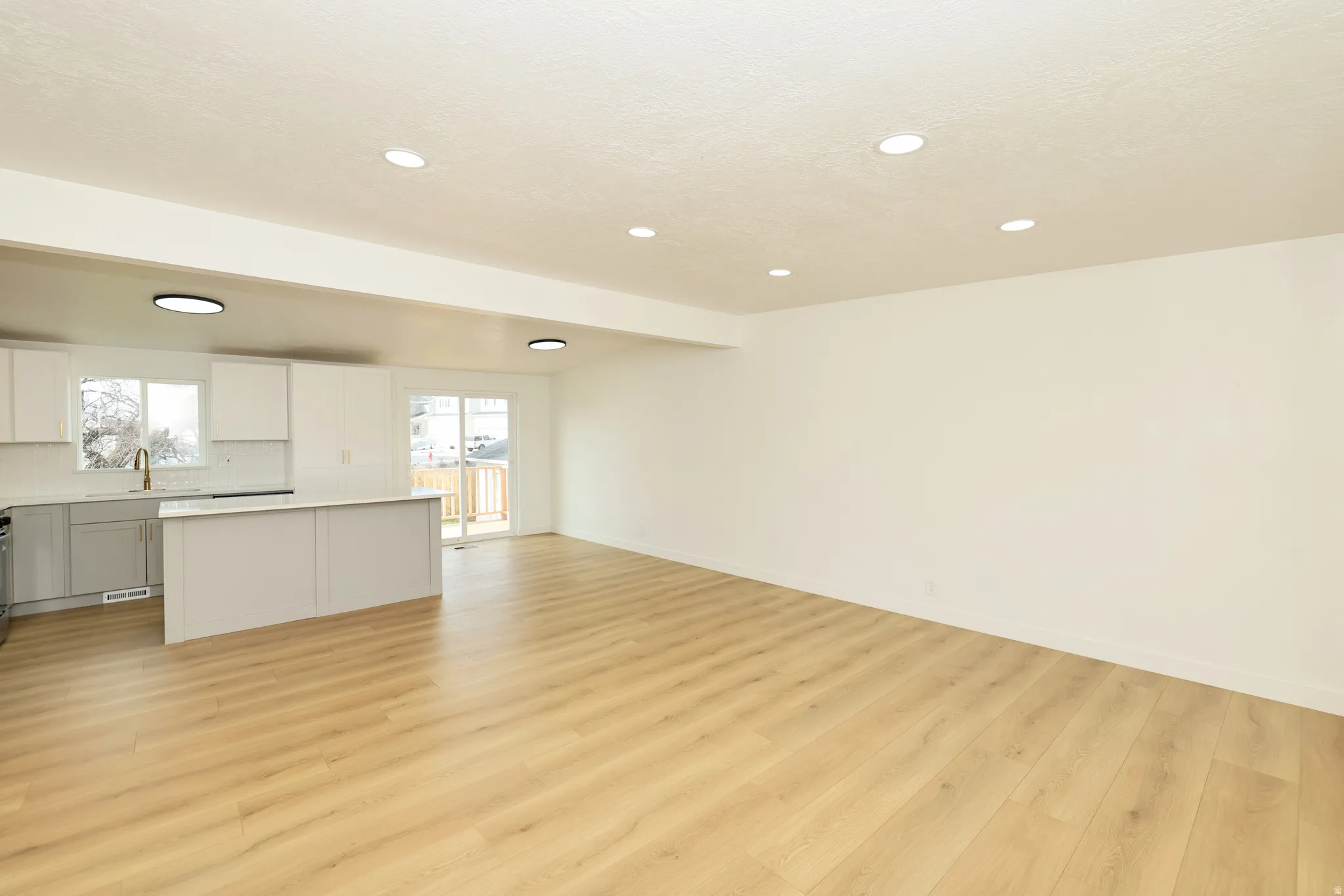 Unfurnished living room with light wood-type flooring, vaulted ceiling, and recessed lighting