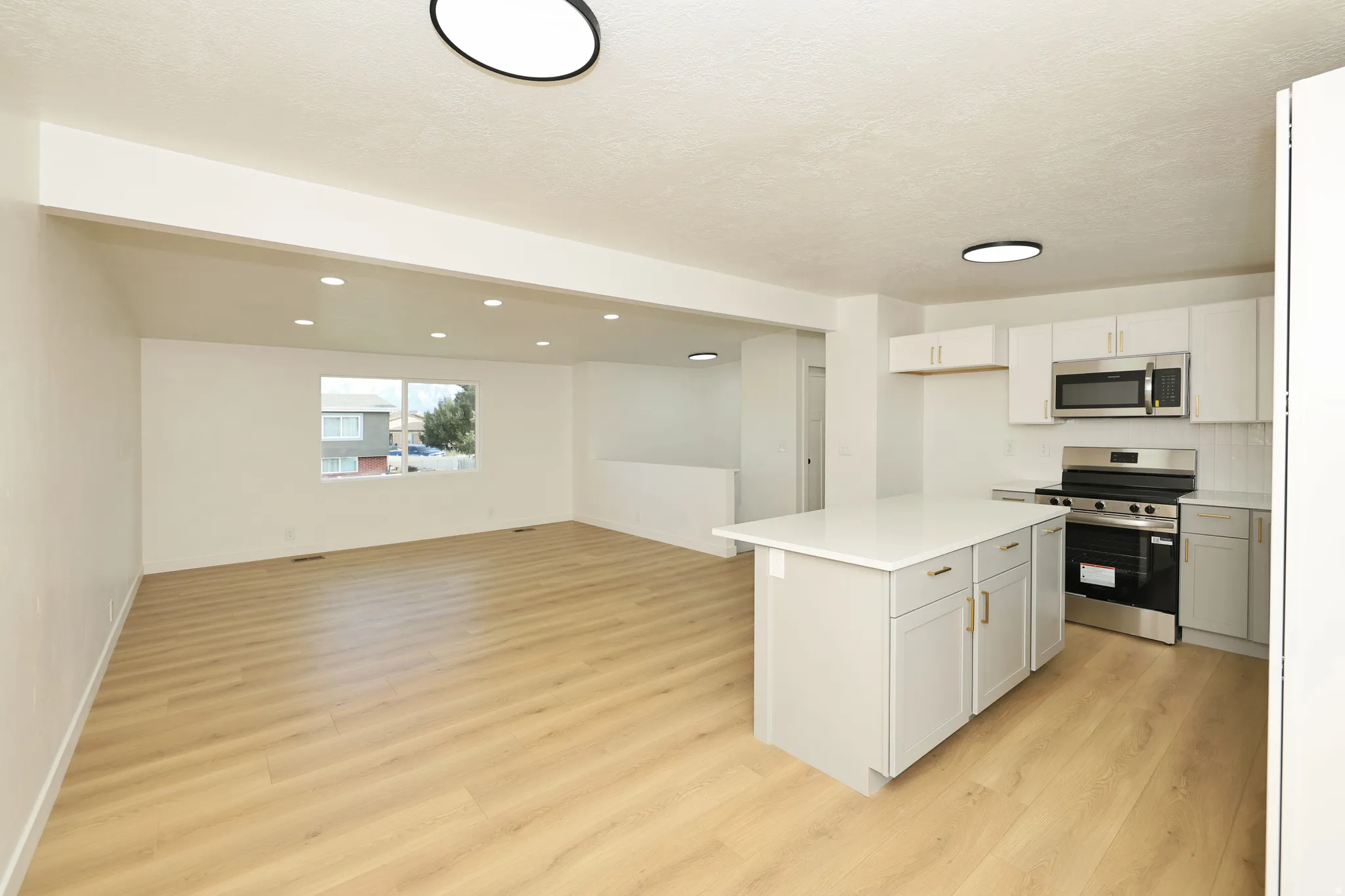 Kitchen with stainless steel appliances, light countertops, light wood-style flooring, open floor plan, and a kitchen island