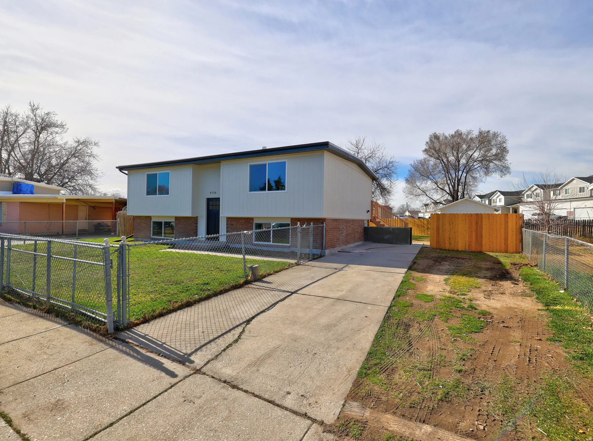 Bi-level home with brick siding, concrete driveway, a fenced front yard, a gate, and a residential view