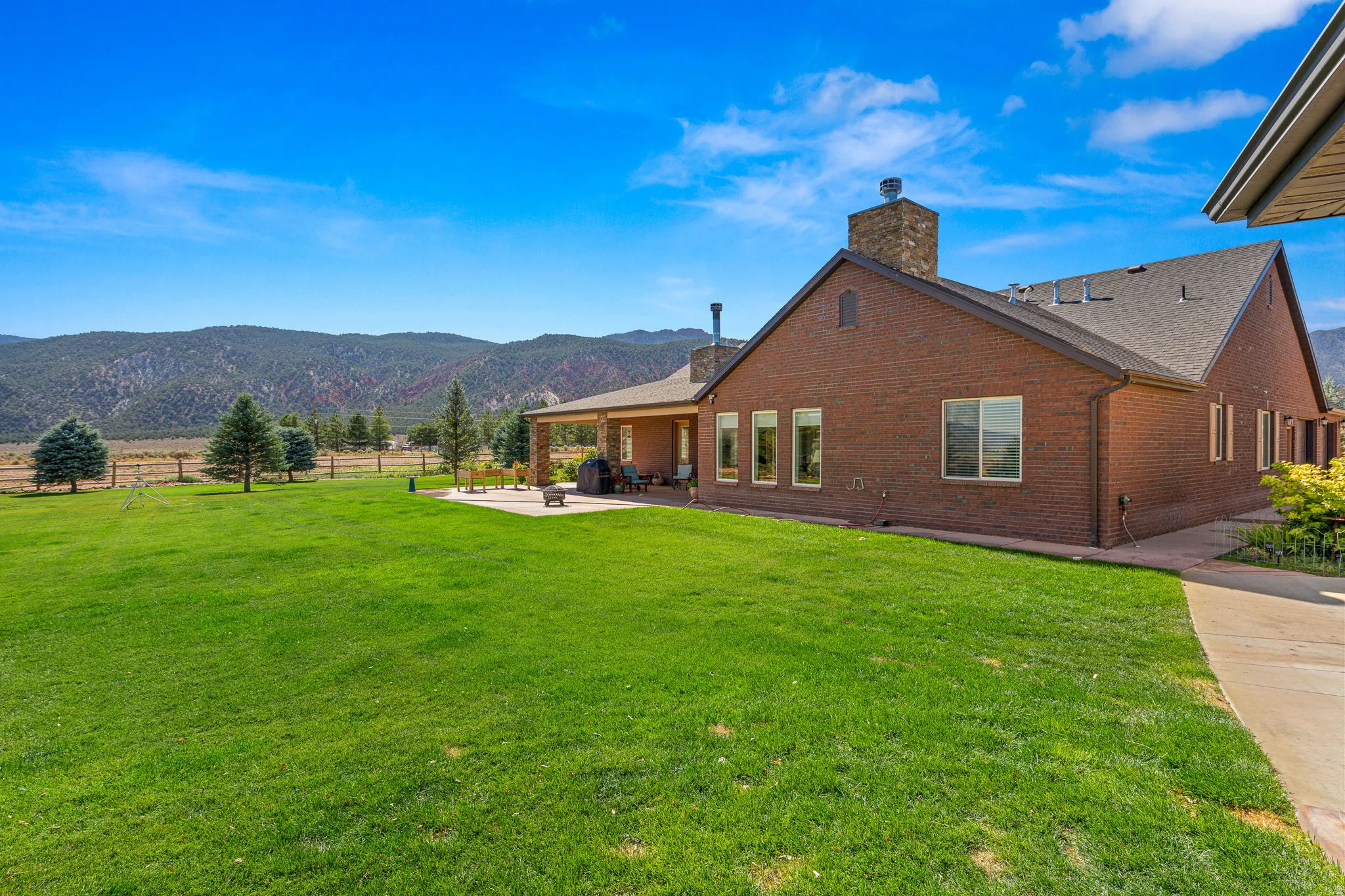 Back of house featuring a chimney, a patio, brick siding, and a mountain view