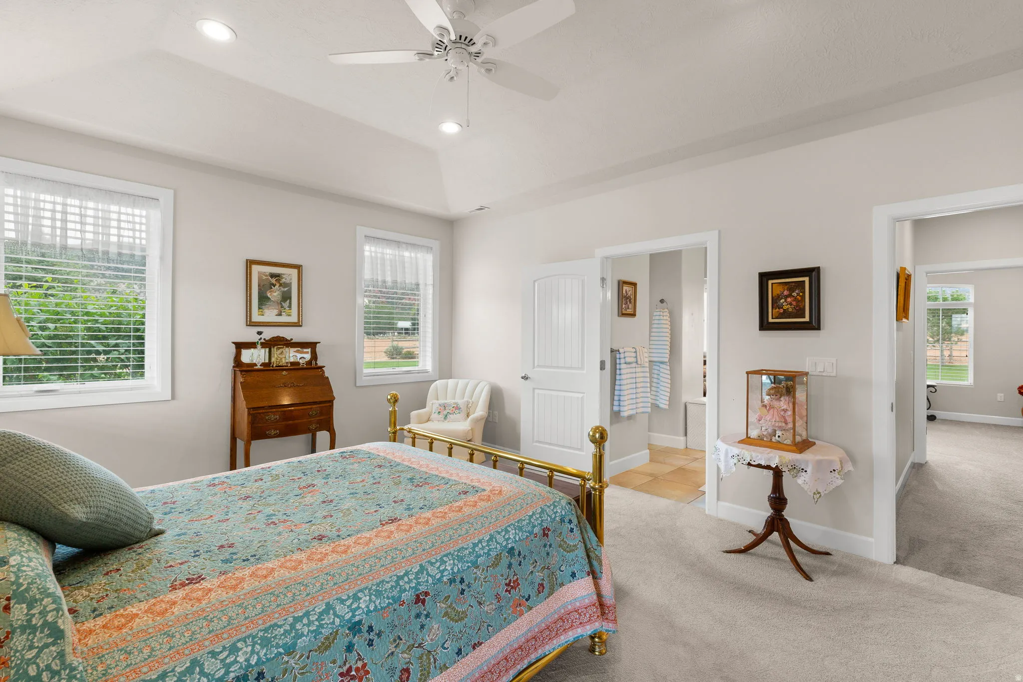 Carpeted bedroom featuring recessed lighting, ceiling fan, a tray ceiling, and ensuite bath
