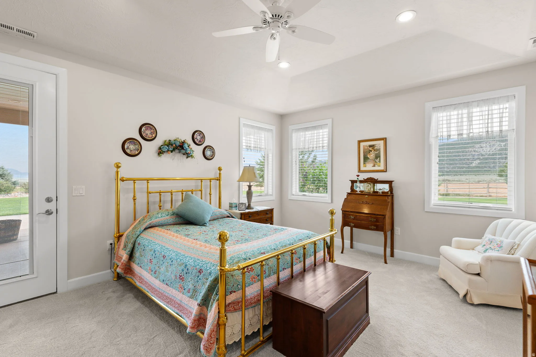 Bedroom featuring multiple windows, light colored carpet, ceiling fan, recessed lighting, and a tray ceiling