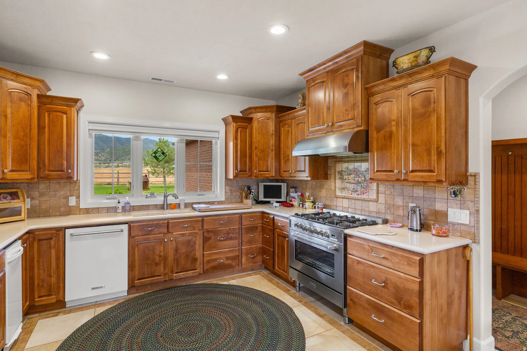 Kitchen with wood finish cabinetry, light countertops, high end stainless steel range, and recessed lighting