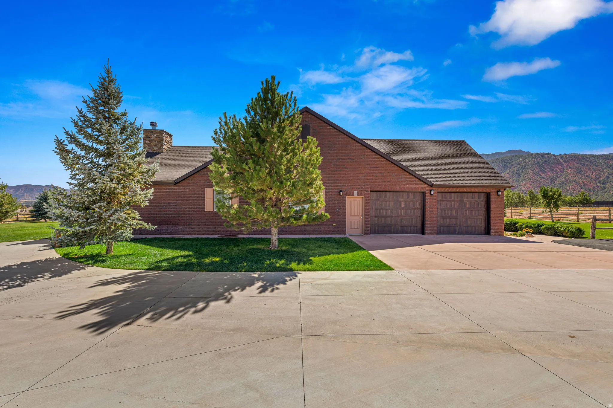 View of front of home with a mountain view, brick siding, driveway, and a chimney