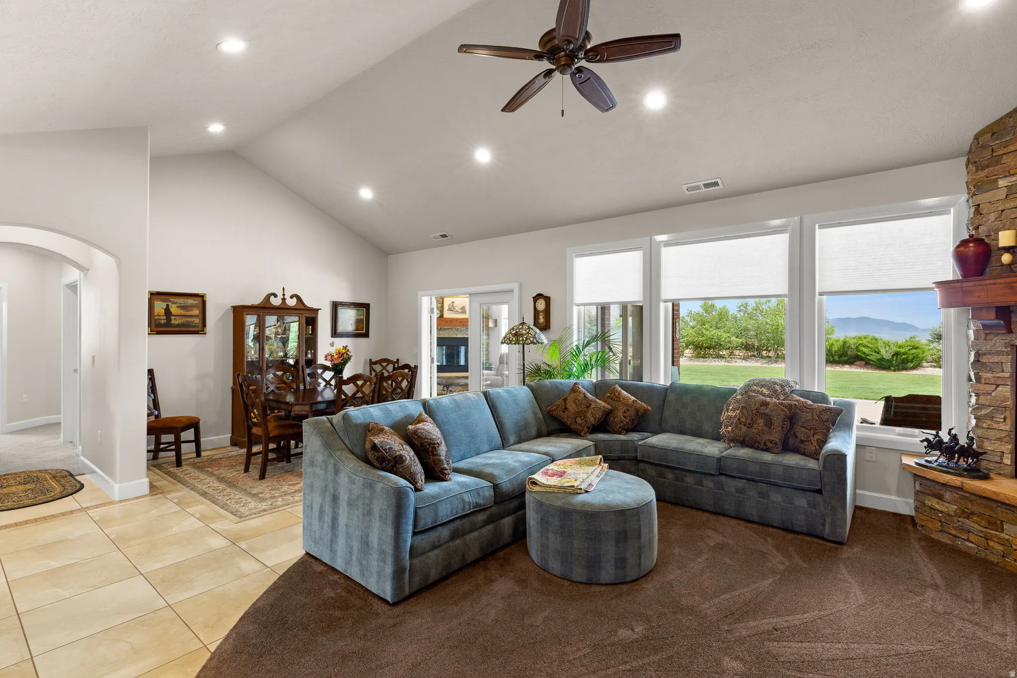 Tiled living room with recessed lighting, arched walkways, a ceiling fan, and a high ceiling