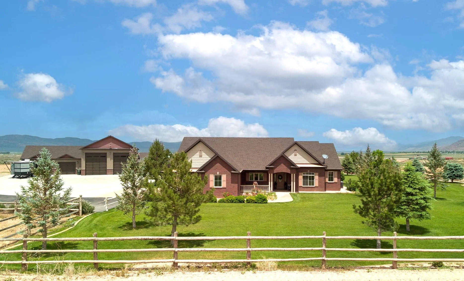 View of front of house with a mountain view, covered porch, a fenced front yard, and a garage
