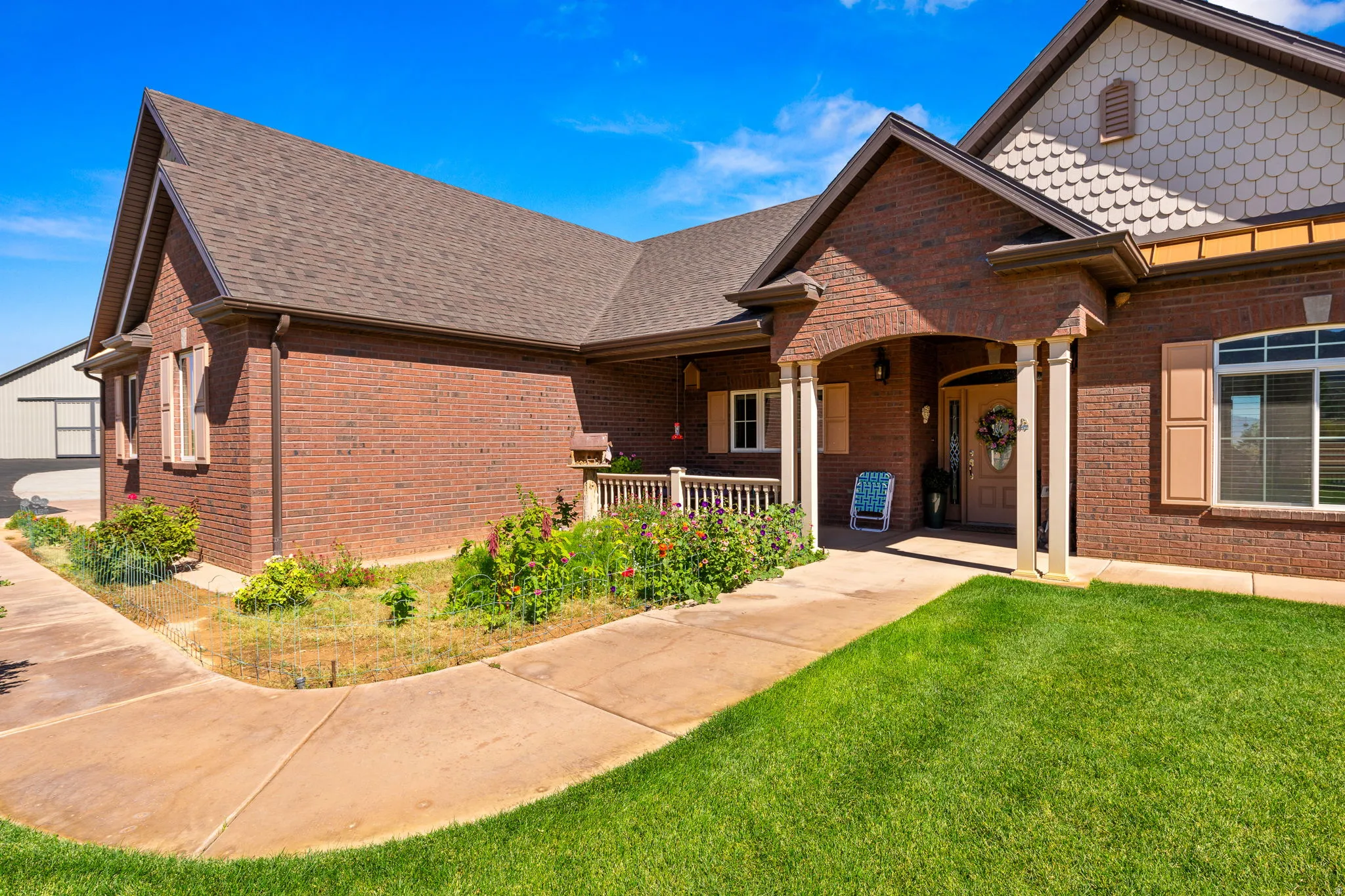 View of front of property with a shingled roof, brick siding, a porch, and a front yard