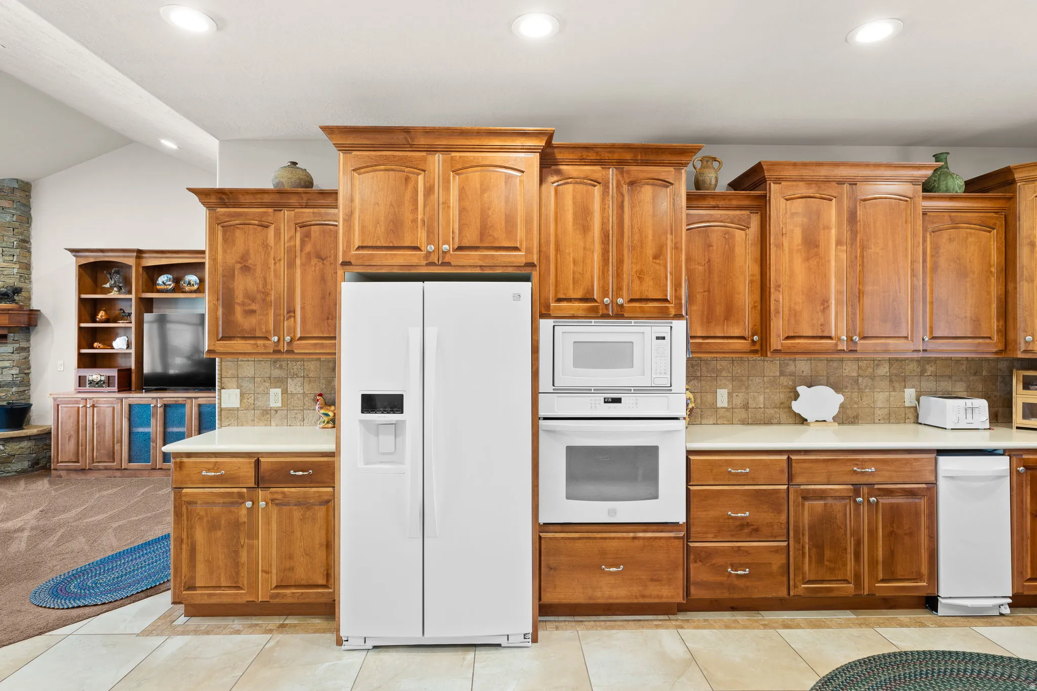 Kitchen featuring white appliances, light countertops, decorative backsplash, wood finish cabinets, and recessed lighting