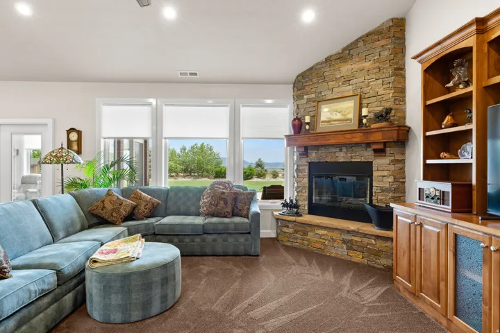 Living area featuring lofted ceiling, dark colored carpet, a stone fireplace, and recessed lighting