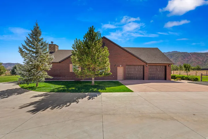 View of front of home with a mountain view, brick siding, driveway, and a chimney