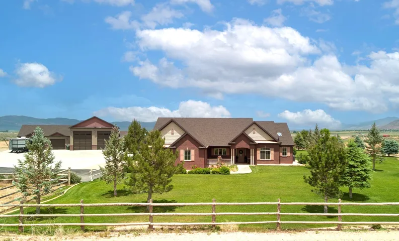 View of front of house with a mountain view, covered porch, a fenced front yard, and a garage