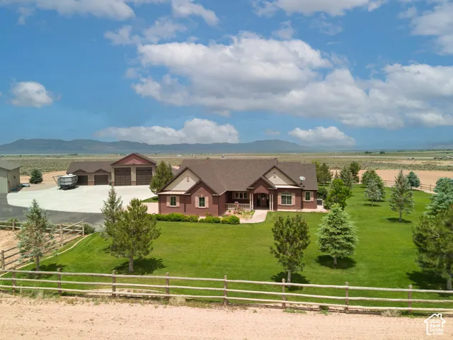 Ranch-style house featuring covered porch, a fenced front yard, brick siding, a mountain view, and a shingled roof