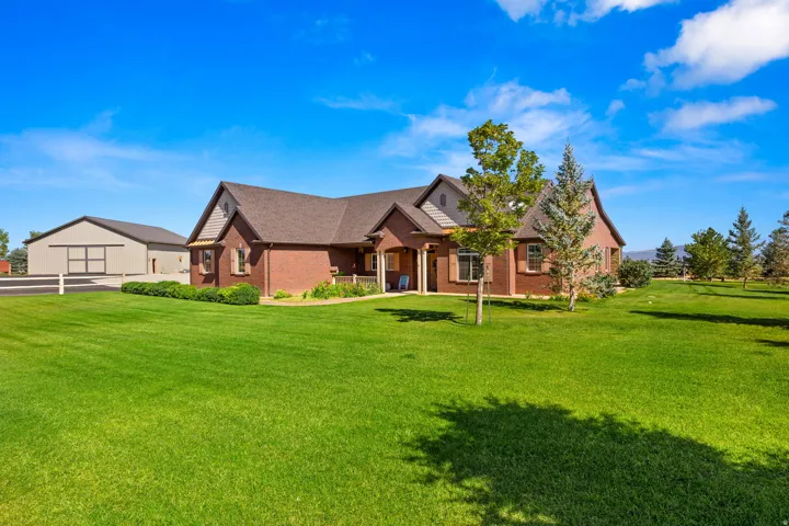 View of front of home featuring a front yard, brick siding, and roof with shingles