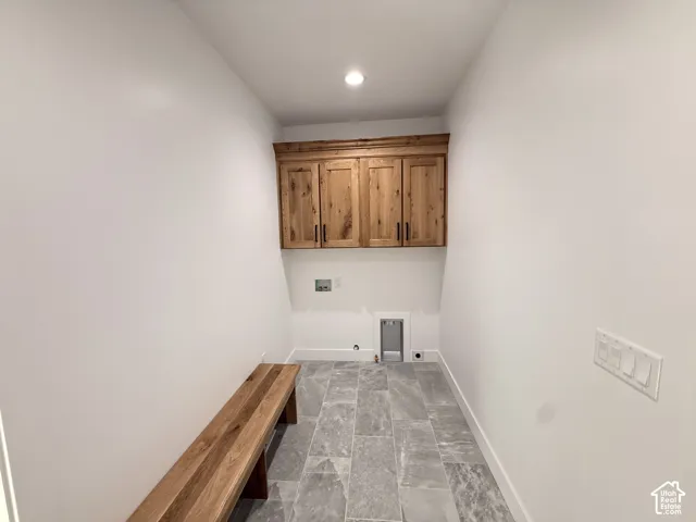 Wall-mounted wood cabinetry, recessed lighting, wood bench, and gray tile flooring