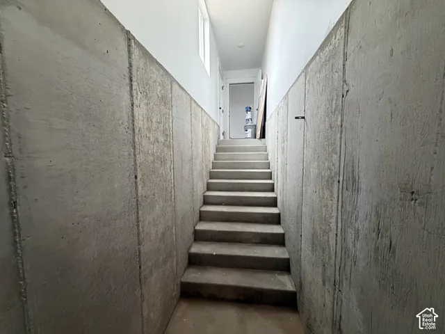 Finished concrete staircase descending between concrete walls and painted upper walls