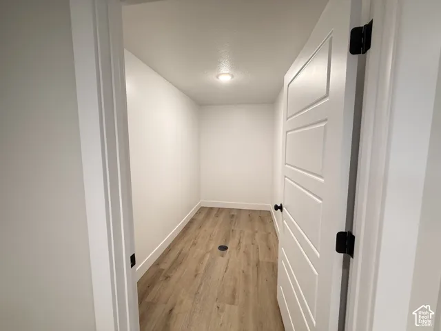 Recessed lighting, wood-finish flooring, white walls, white trim, and a paneled door with matte black hardware
