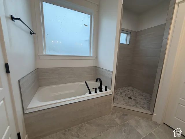 Bathroom featuring an integrated soaking tub with matte black fixtures, a tiled surround, and a frosted window