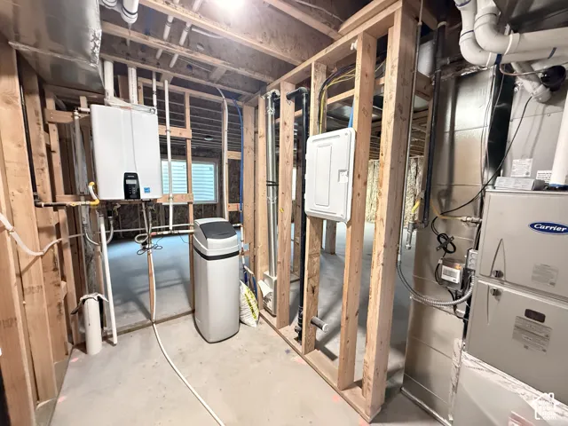 Unfinished basement featuring a tankless water heater, water softener, electrical panel, and HVAC system
