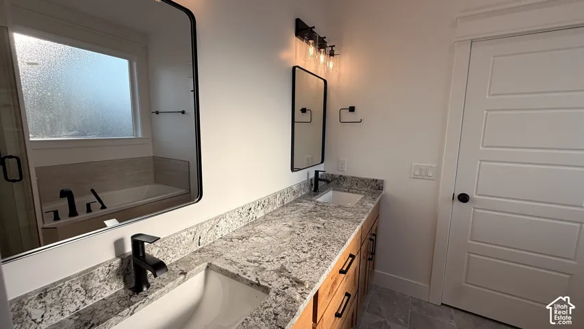 Dual vanity with light-toned countertop and integrated sinks, wood-finish cabinetry with matte black hardware, and coordinating matte black faucets