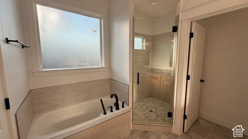Built-in tub with matte black fixtures, tile surround, and an adjacent glass-enclosed shower with a tiled floor