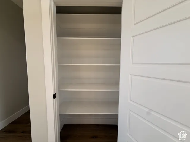 Built-in shelving with multiple levels, white panel door, and dark wood-finish flooring