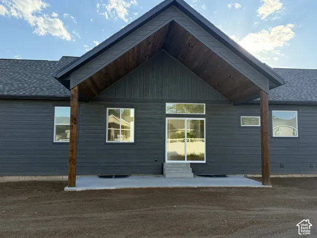 Covered patio area featuring a dark gray exterior, wood-finish columns, a vaulted wood-finish ceiling with recessed lighting, and a sliding glass door