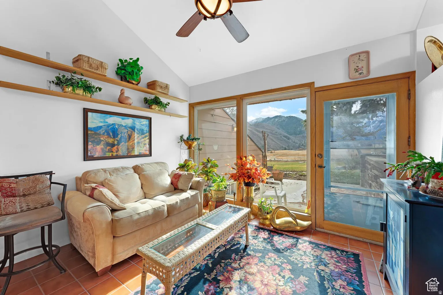 Living room featuring a mountain view, lofted ceiling, a ceiling fan, and light tile patterned floors