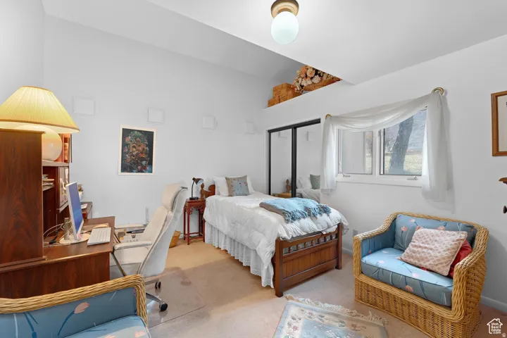 Bedroom featuring carpet flooring, an office area, a closet, and lofted ceiling
