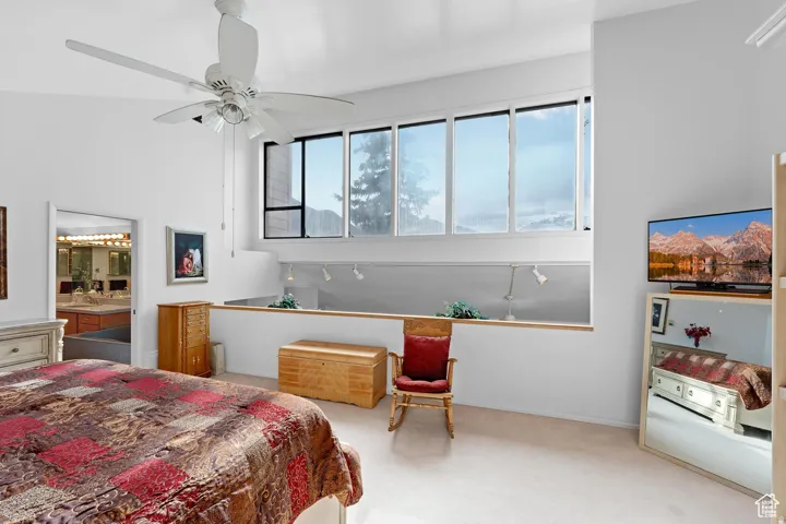 Primary Bedroom featuring light carpet, ceiling fan, and ensuite bathroom