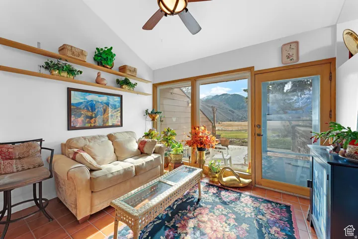 Living room featuring a mountain view, lofted ceiling, a ceiling fan, and light tile patterned floors