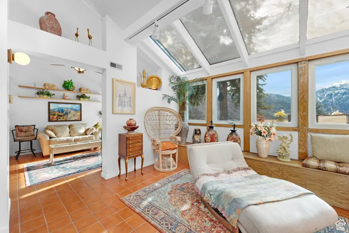 Living area featuring a skylight, healthy amount of natural light, light tile patterned floors, vaulted ceiling, and a mountain view