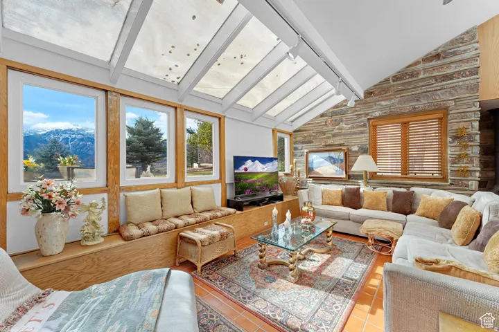 Tiled living area featuring plenty of natural light, vaulted ceiling, and a mountain view