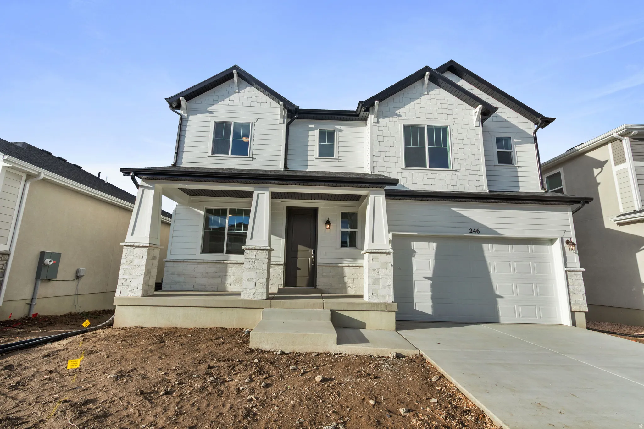 Craftsman inspired home featuring stone siding, a garage, covered porch, and concrete driveway
