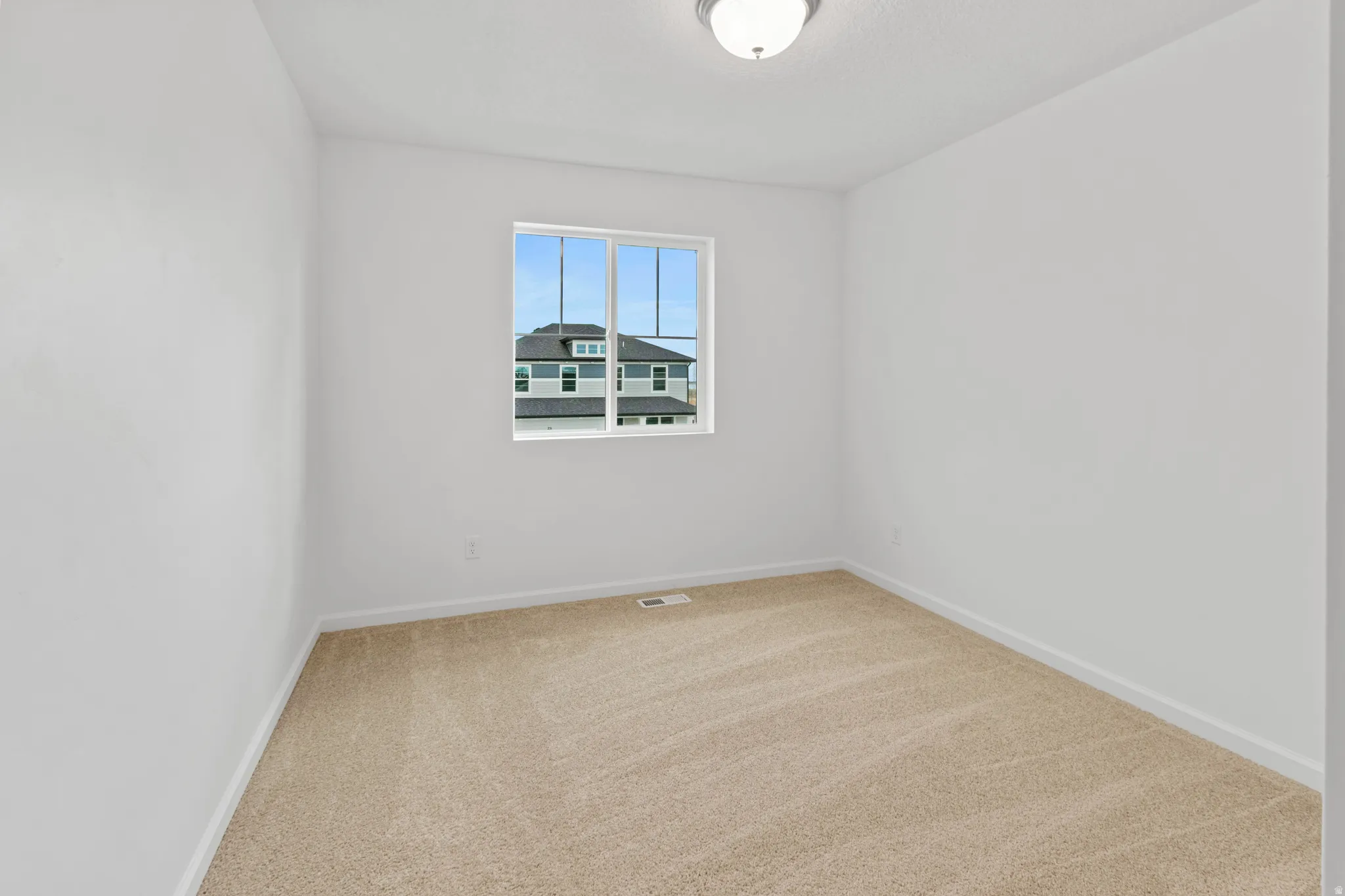 Spare room featuring light colored carpet and baseboards