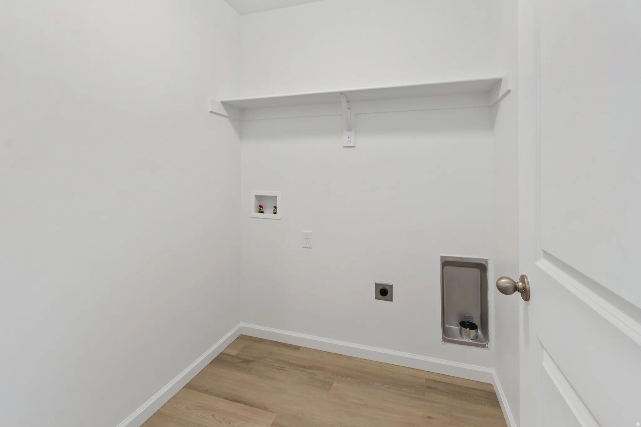 Laundry area with light wood finished floors, hookup for an electric dryer, and hookup for a washing machine