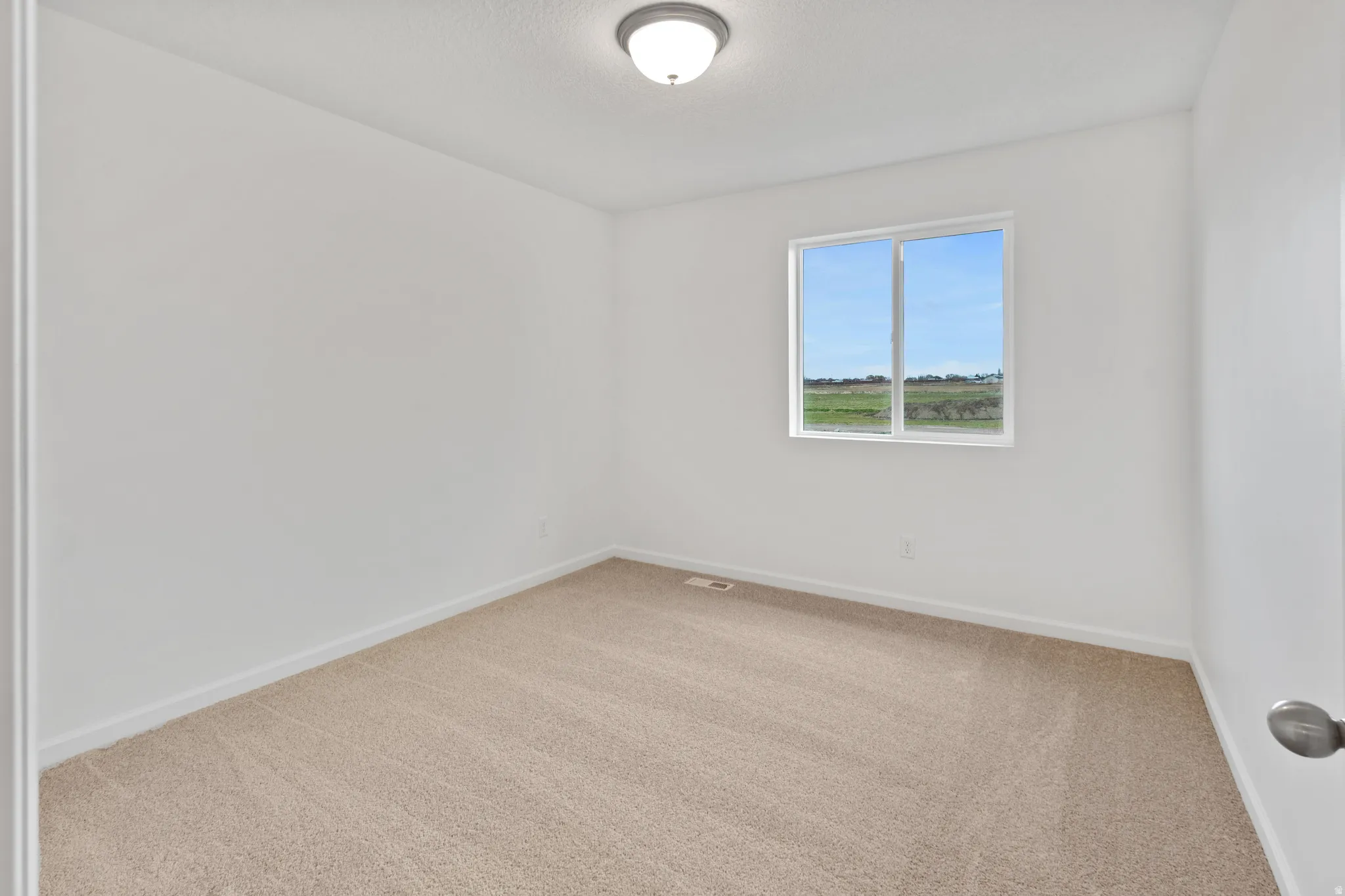 Spare room with light carpet and a textured ceiling