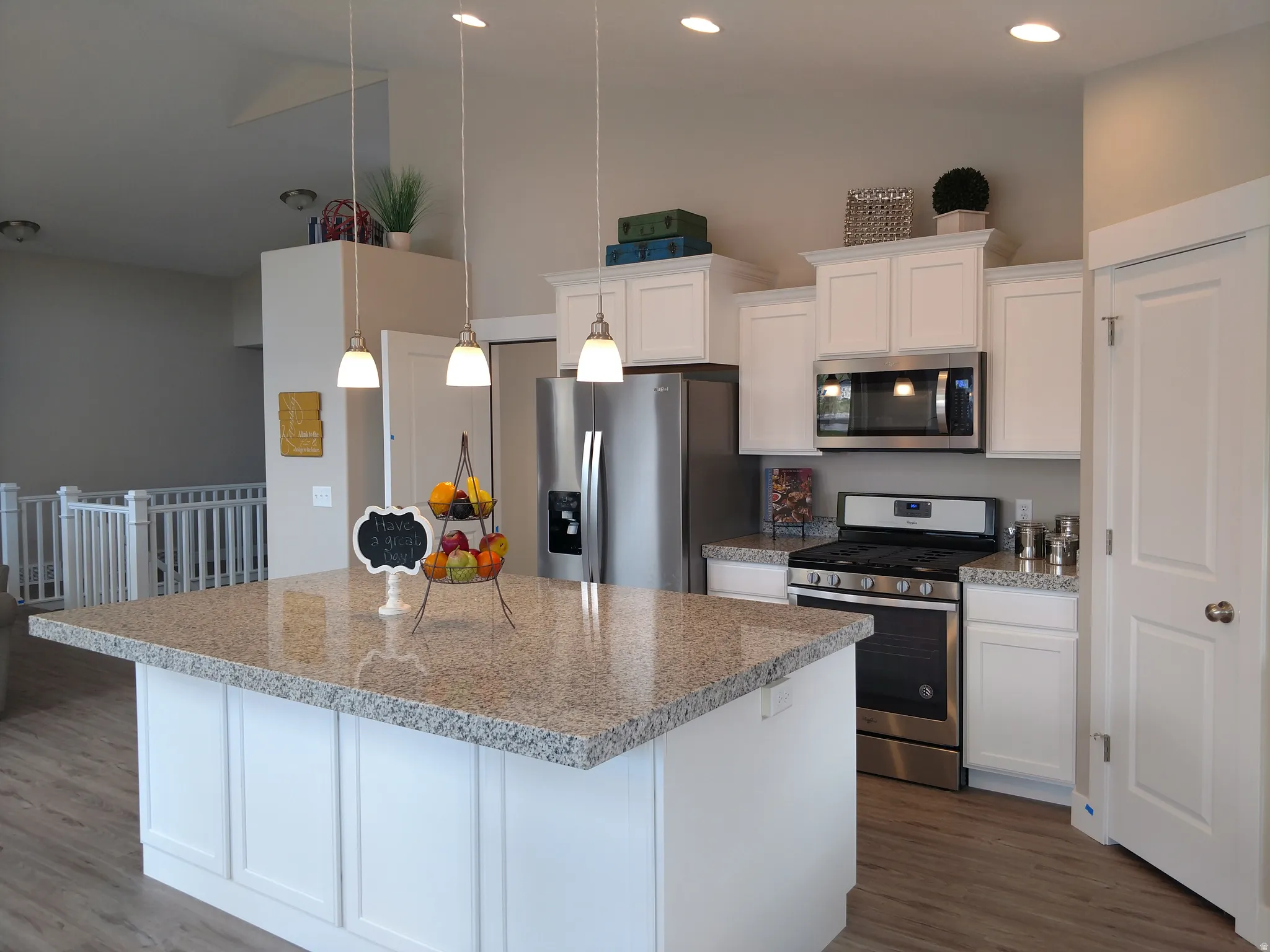 Kitchen with stainless steel appliances, white cabinetry, light stone counters, dark wood-style flooring, and vaulted ceiling
