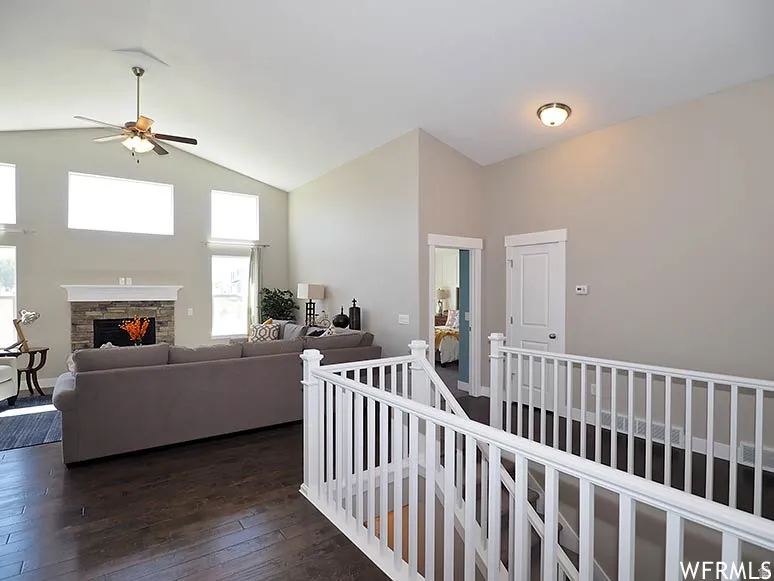 Corridor with dark wood-style flooring, vaulted ceiling, and an upstairs landing