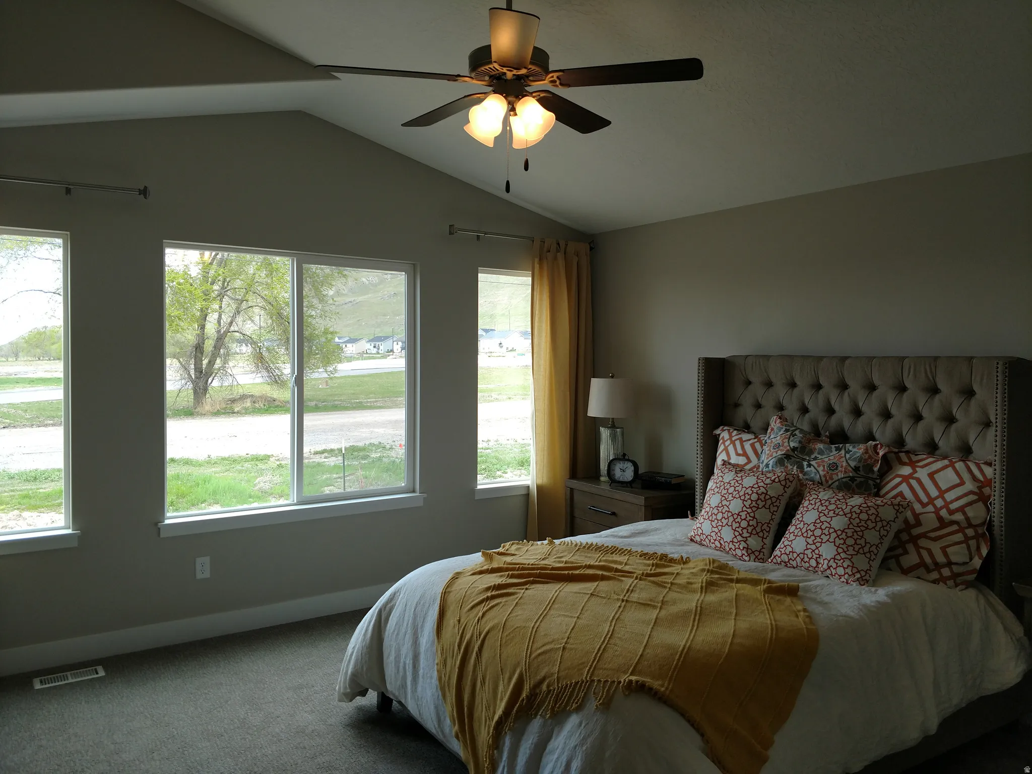 Carpeted bedroom featuring vaulted ceiling and ceiling fan