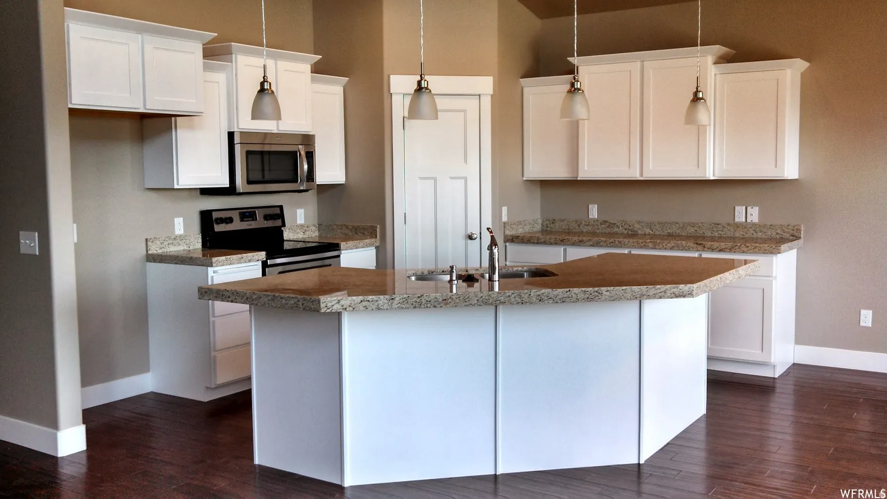 Kitchen featuring stainless steel appliances, a center island with sink, white cabinets, dark wood-style flooring, and decorative light fixtures