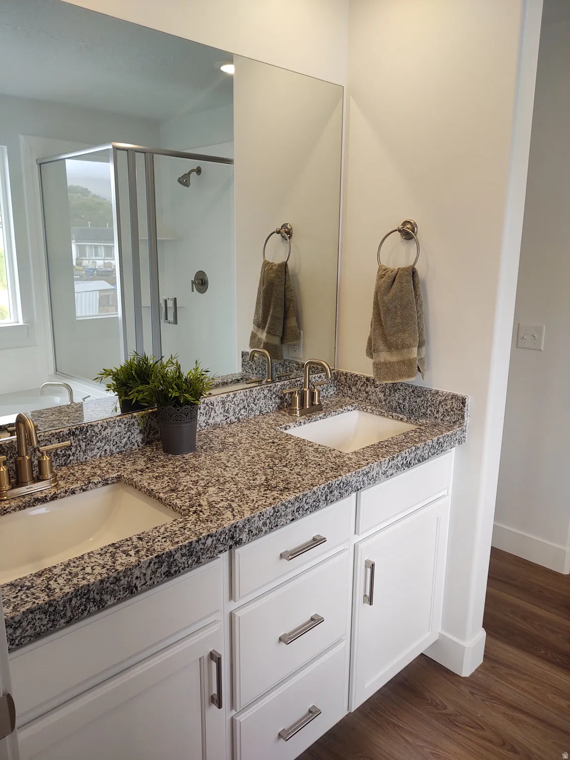 Bathroom with double vanity, a shower stall, dark wood-style floors, and a bath