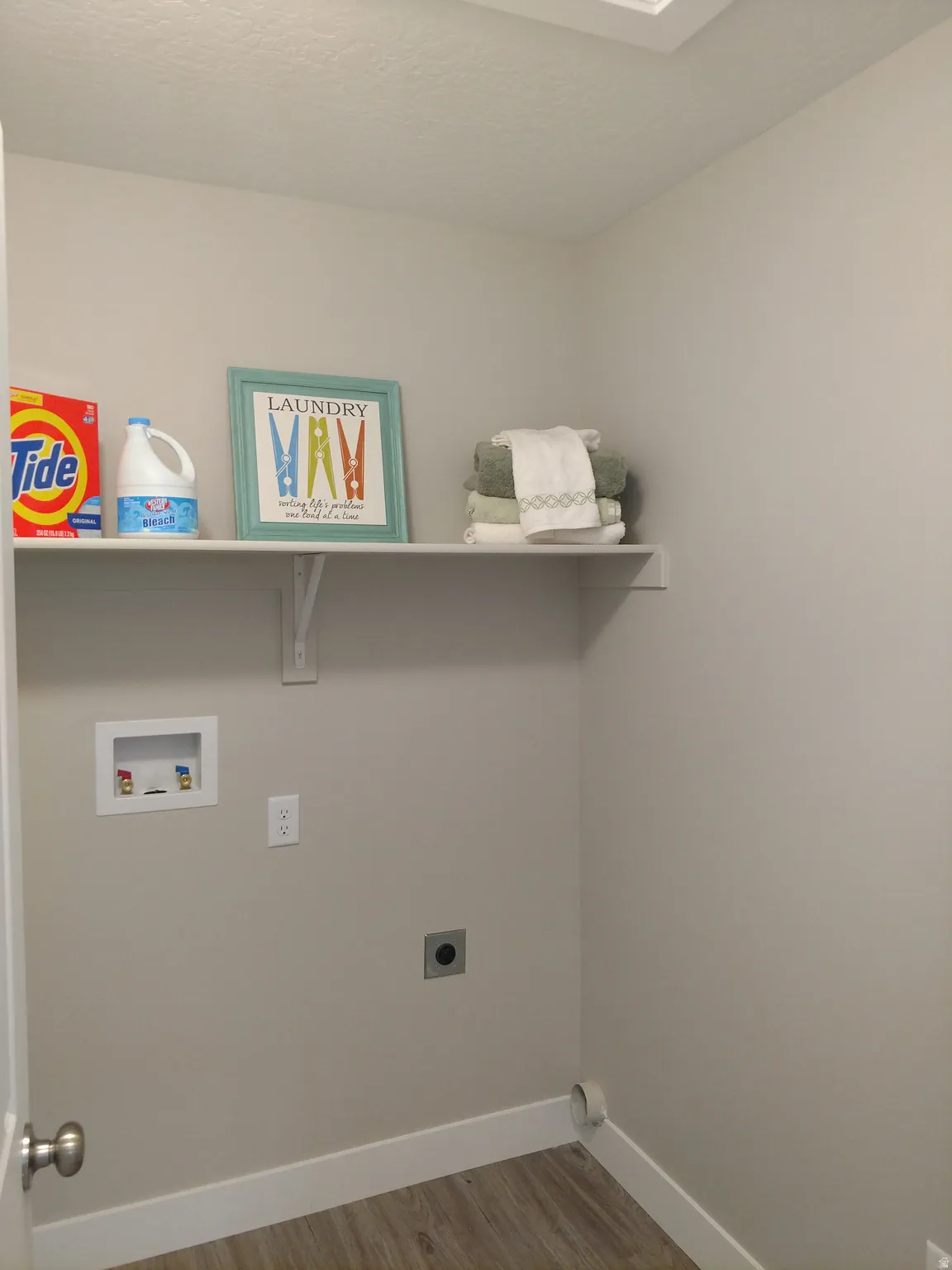 Laundry area with hookup for an electric dryer, light wood-style floors, and hookup for a washing machine