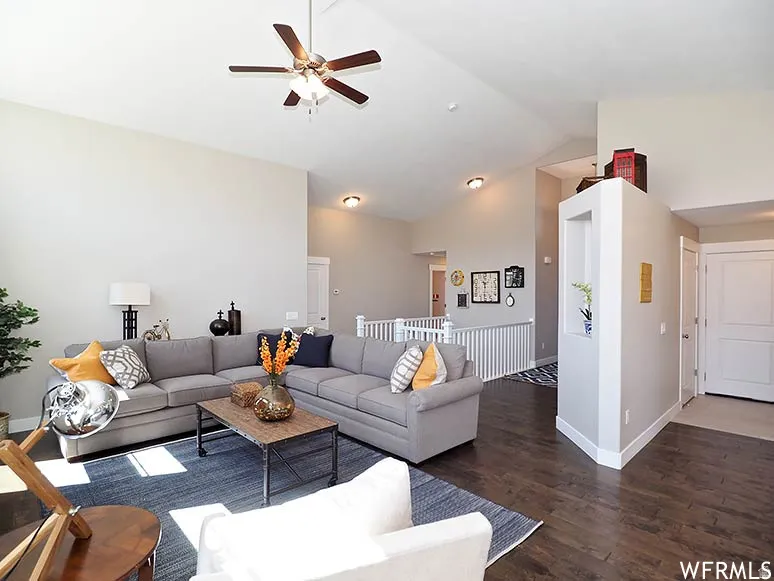Living room with ceiling fan, wood finished floors, and vaulted ceiling