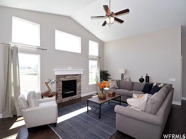 Living area with a ceiling fan, dark wood-style flooring, a high ceiling, and a fireplace