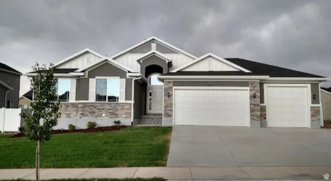 Craftsman house featuring stone siding, an attached garage, a front lawn, and driveway