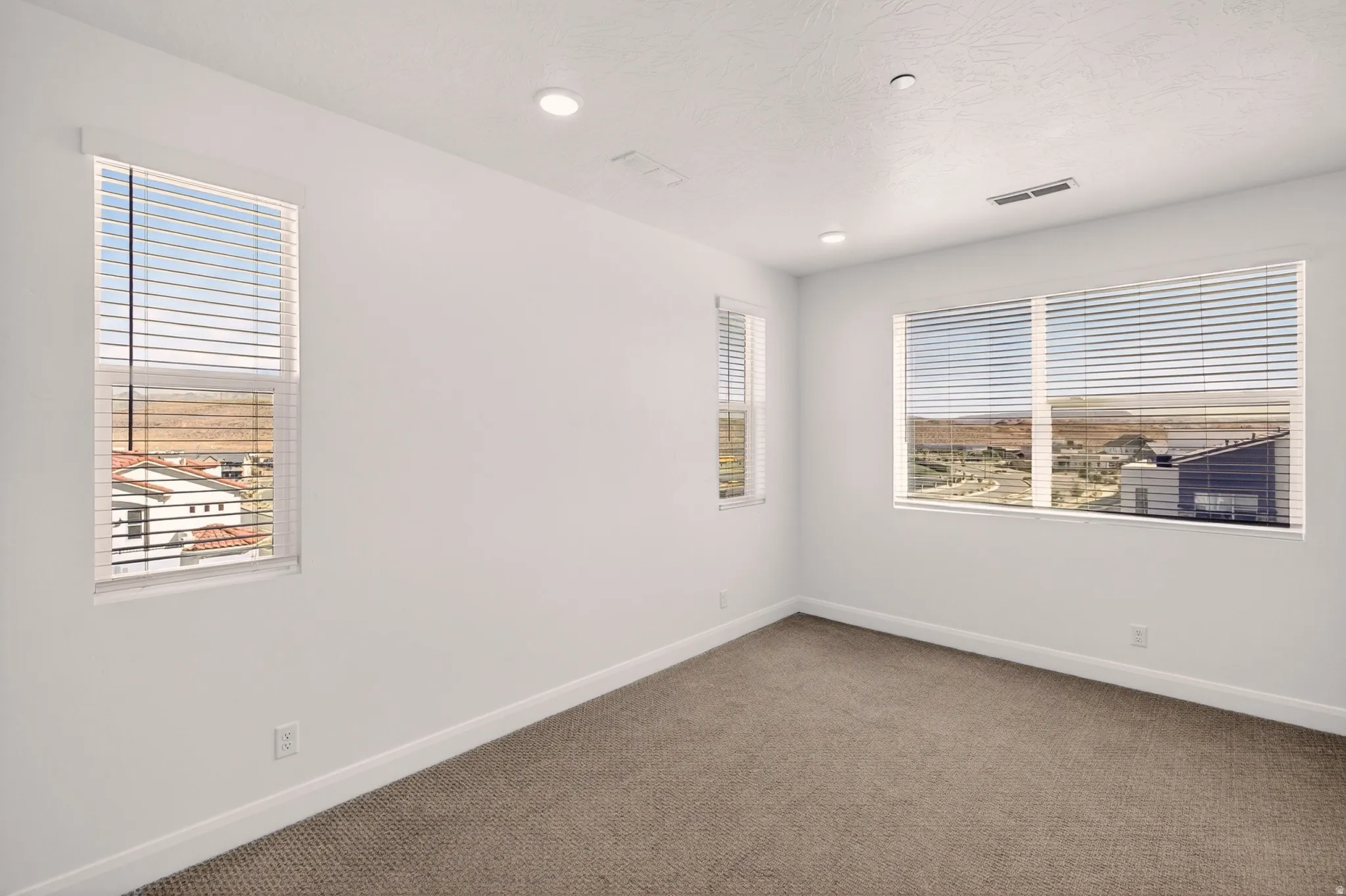Carpeted spare room with baseboards and recessed lighting