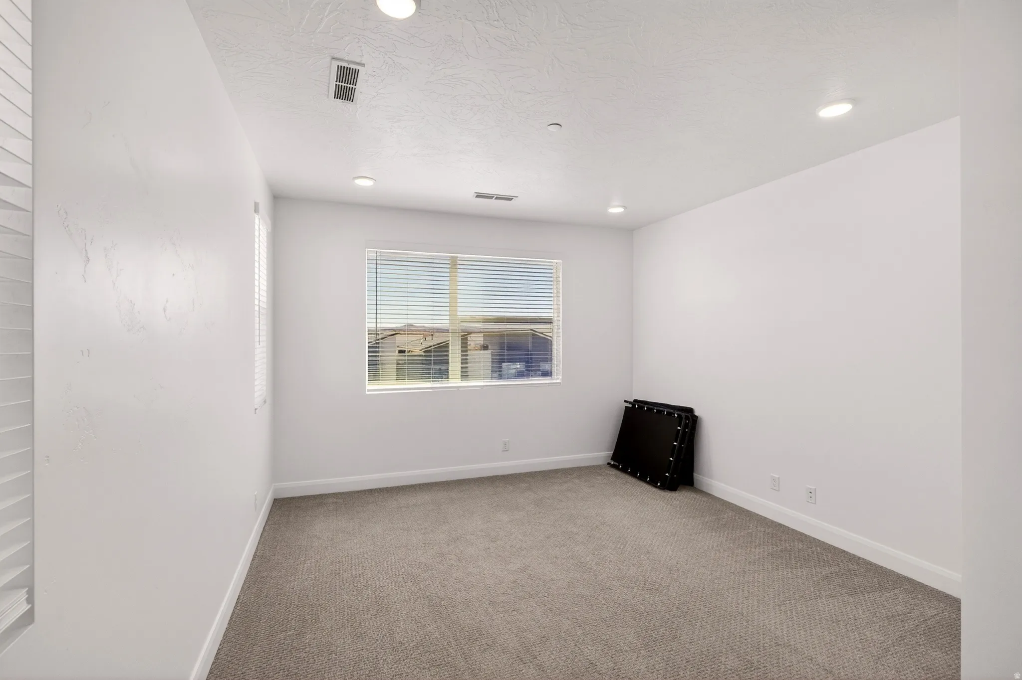 Empty room with light colored carpet and baseboards