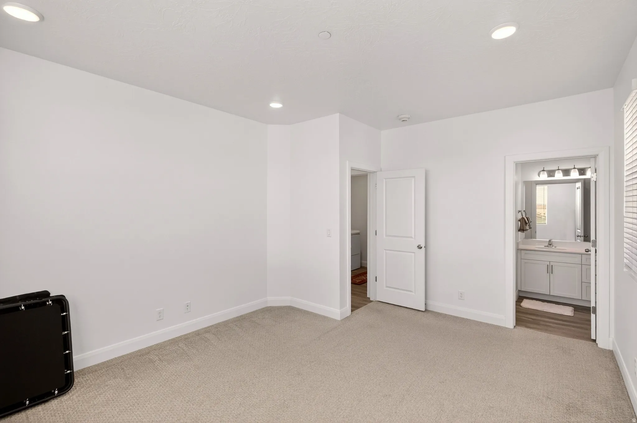 Unfurnished bedroom featuring light colored carpet, ensuite bath, and recessed lighting