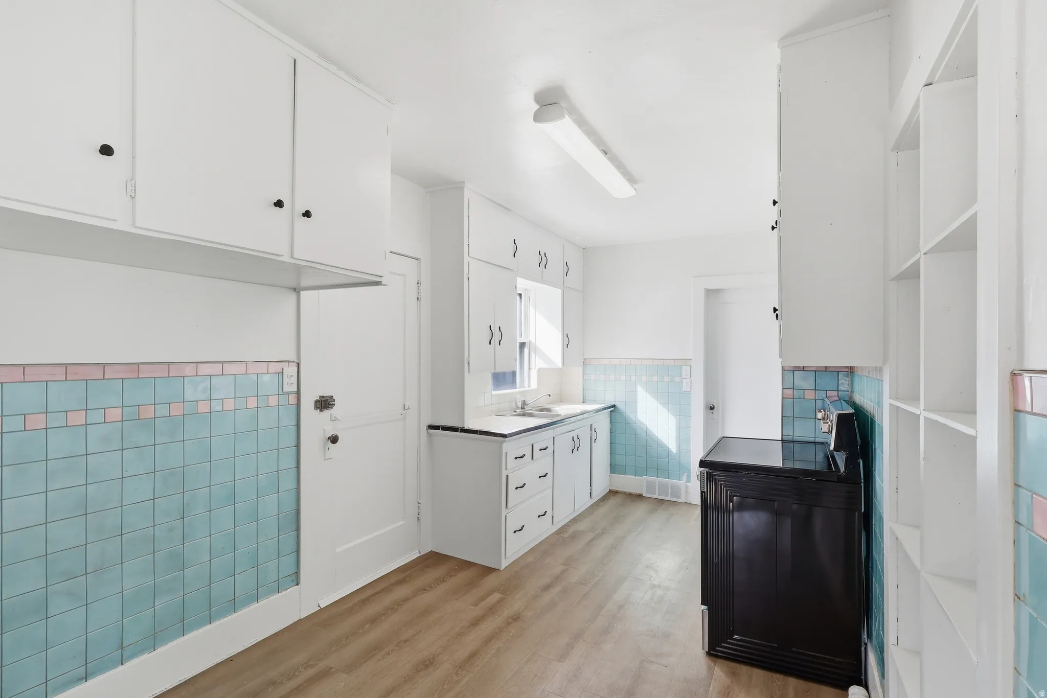 Kitchen featuring white cabinetry, a wainscoted wall, tile walls, and light wood-style floors