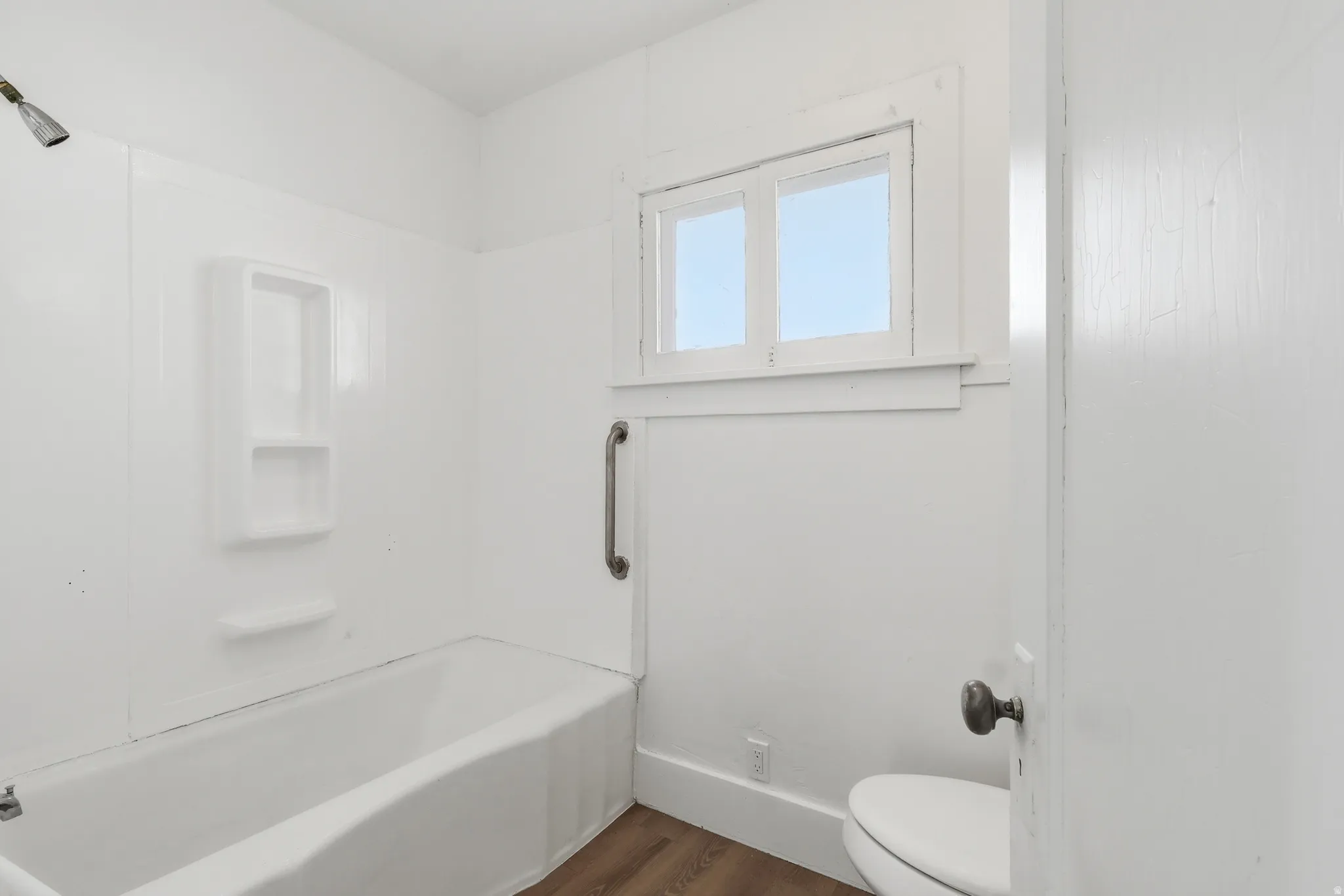 Full bath featuring dark wood finished floors and washtub / shower combination